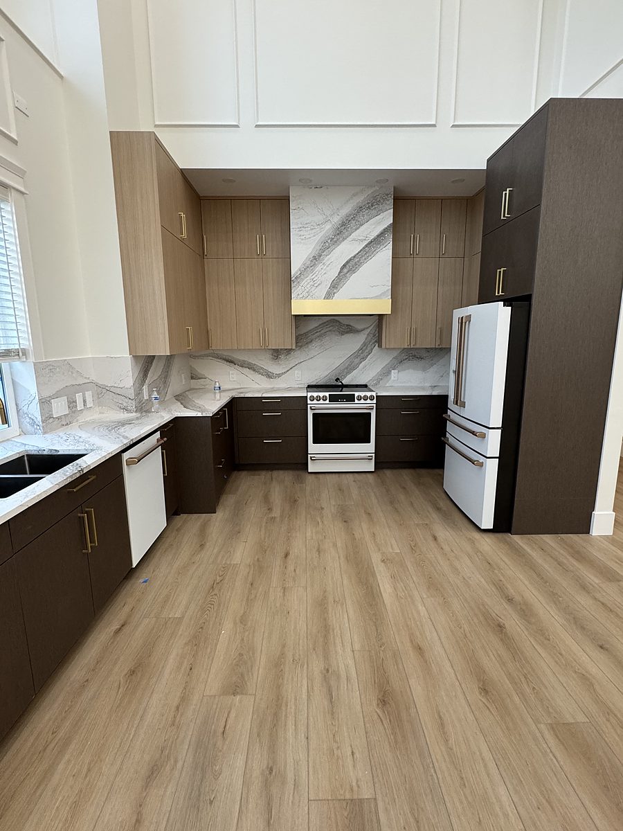 Finished kitchen with two-tone cabinetry, marble-look quartz backsplash and brass hardware