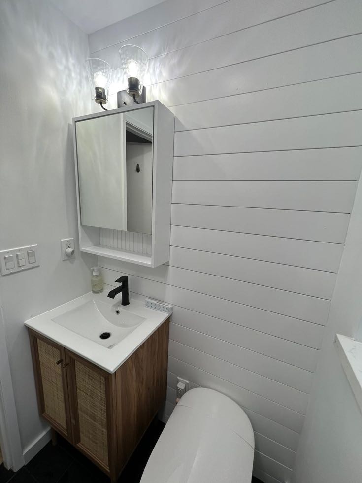 Powder room with shiplap wall and wood vanity